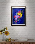 Framed The Color of Happiness floral painting by Kris Horton on a white brick wall above a wooden console table.