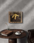 Framed artwork of a red tail hawk's foot painted by Kris Horton on a textured wall above a wooden table with a notebook and coffee cup.