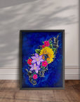 Framed artwork by Kris Horton, with colorful floral design on a blue background, displayed leaning on a wall.