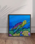 Framed artwork by Kris Horton of a turtle on a coral reef against a blue background, displayed on a wooden floor.