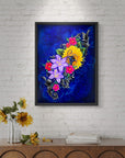 Framed floral artwork named Color of Happiness by Kris Horton on a white brick wall with a wooden console table.