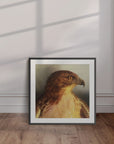 Black framed artwork by Kris Horton of Watchful a red tail hawk painting leaning against a wall.