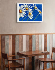 Daisy Days framed canvas print, a painting by Kris Horton, hanging over a table.