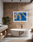Framed Daisy Days floral painting by Kris Horton with five white daisies on a blue background styled in a modern bathroom.