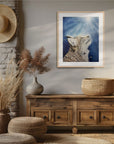 Framed wall art by Kris Horton of Believe a bobcat painting with a blue background nestled corner of a room with rustic decor.