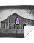 Blanket with a black and white barn design featuring an American flag, on a white background.