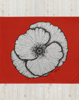 Black ink drawing of a poppy with a red background by Kris Horton on a throw blanket