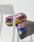 Painting of a cross made of vibrant flowers by Kris Horton on a blanket that is rolled up