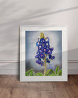 White framed Texas Bloom No. 1 bluebonnet painting by Kris Horton leaning on a wall.