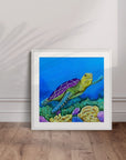 Framed artwork by Kris Horton of a turtle in an underwater scene leaning on a white wall.