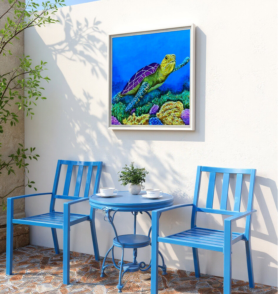 Framed painting by Kris Horton, Sea of Colors, a vibrant sea turtle in blue water above coral, hanging on a patio with blue chairs.