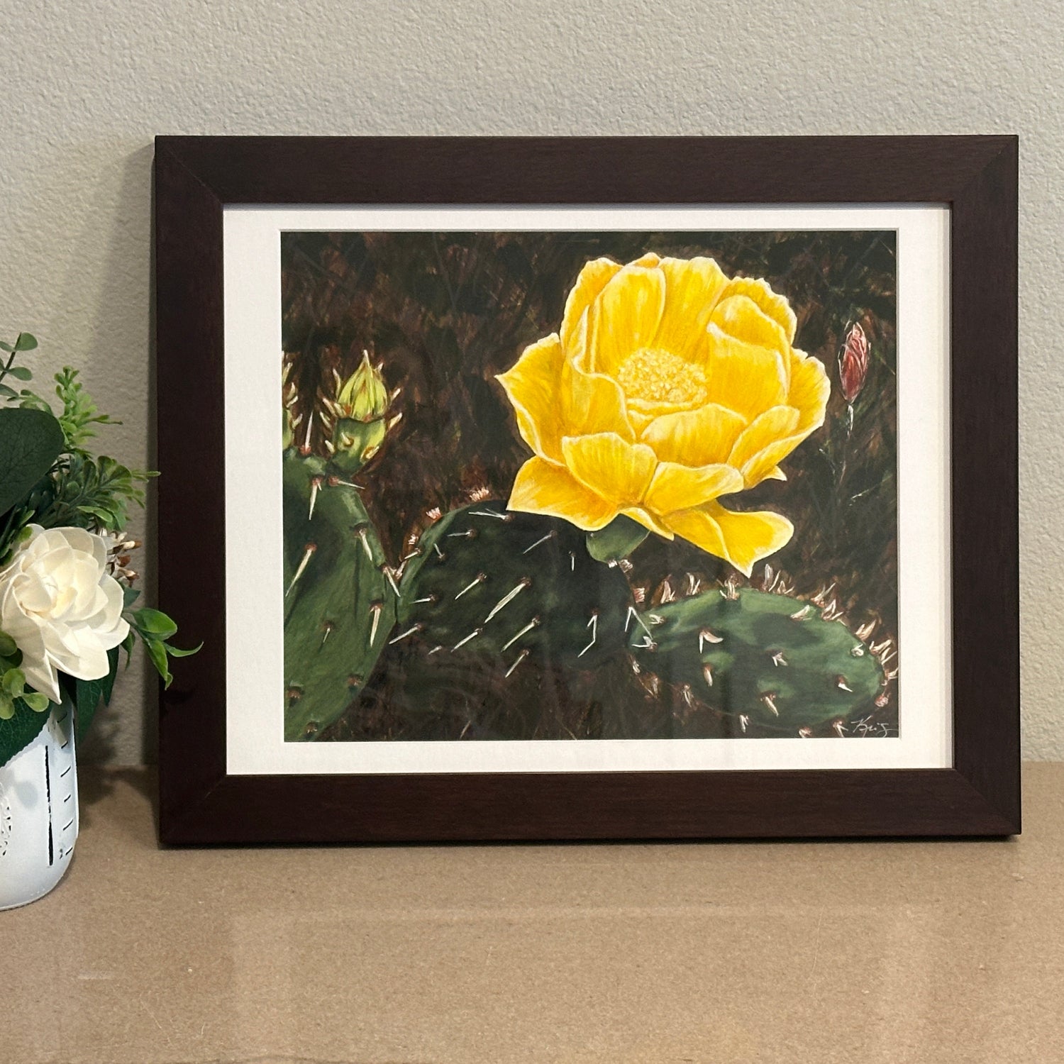 Framed artwork by Kris Horton of a yellow cactus flower on a neutral background
