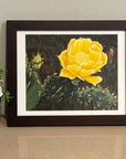 Framed artwork by Kris Horton of a yellow cactus flower on a neutral background