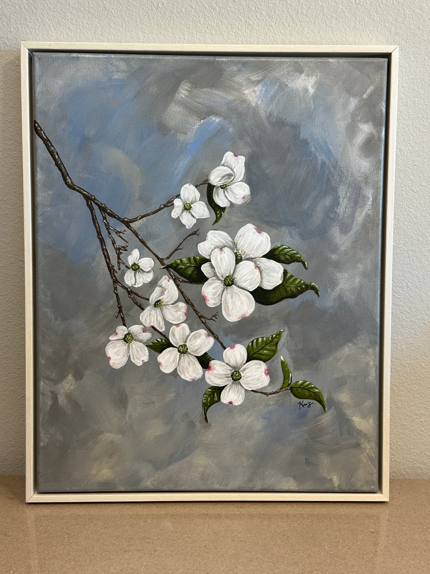 Framed painting by Kris Horton of a branch with dogwood flowers on a textured wall.