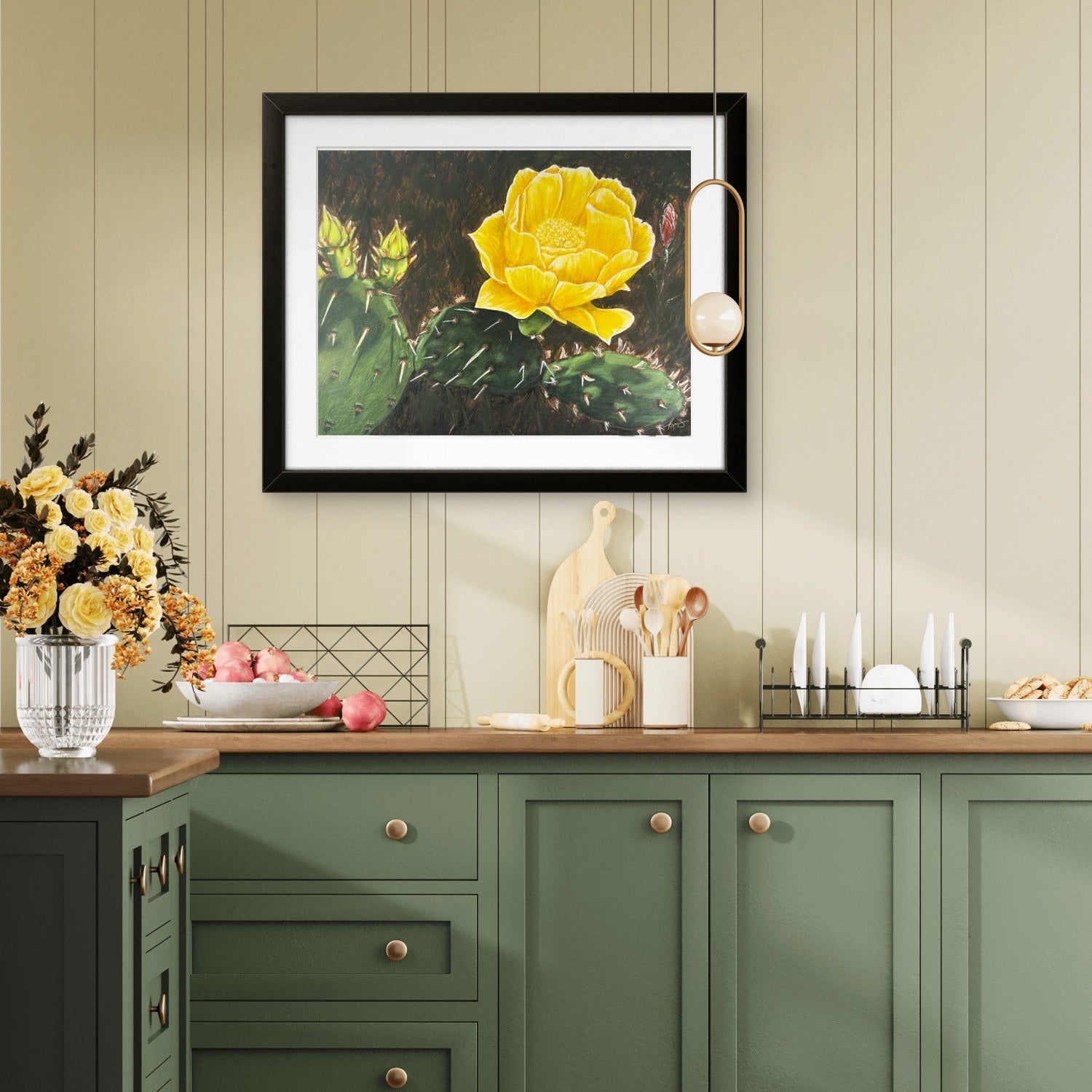 Beauty Among Thorns a cactus art print with a yellow flower painted by Kris Horton hanging in a kitchen with green cabinets