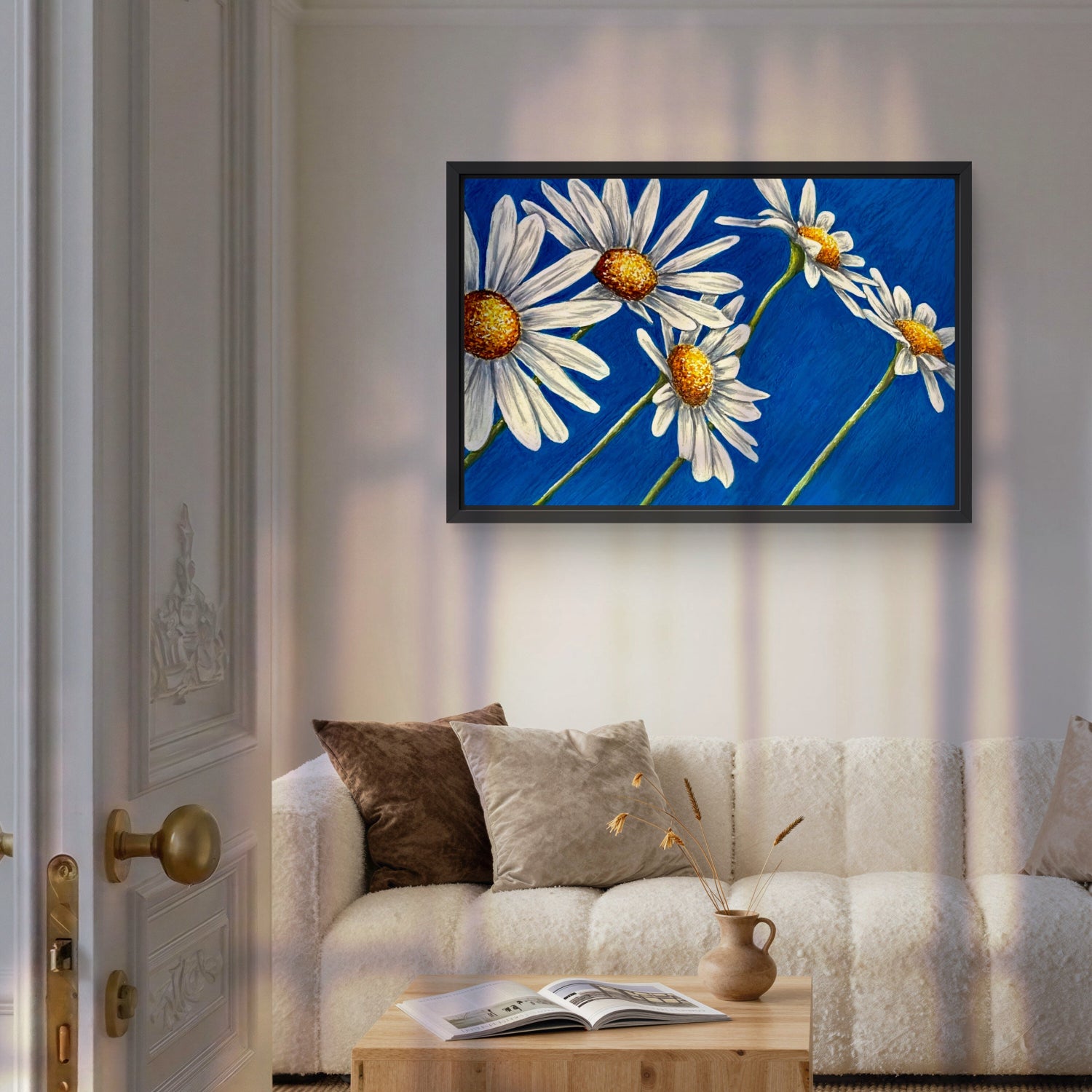 Daisy Days framed painting by Kris Horton of five daisies with blue background over couch.
