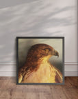 Black framed painting by Kris Horton of a close up red tail hawk leaning against the wall.