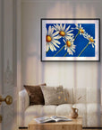 Daisy Days framed painting by Kris Horton of 5 daisies with blue background above a couch