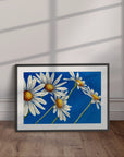 Black framed Daisy days painting by Kris Horton which is a daisy painting with blue abstract background