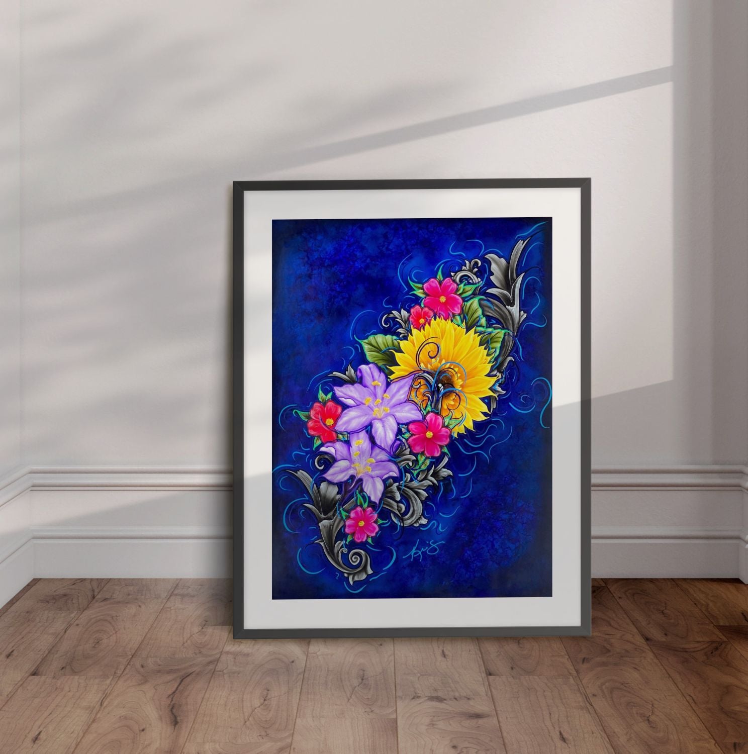 Framed artwork of colorful flowers on a blue background displayed leaning against a wall.