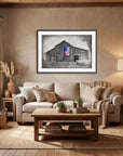 Framed painting by Kris Horton of My America a black and white old barn and truck and an American Flag in color hanging in rustic living room.