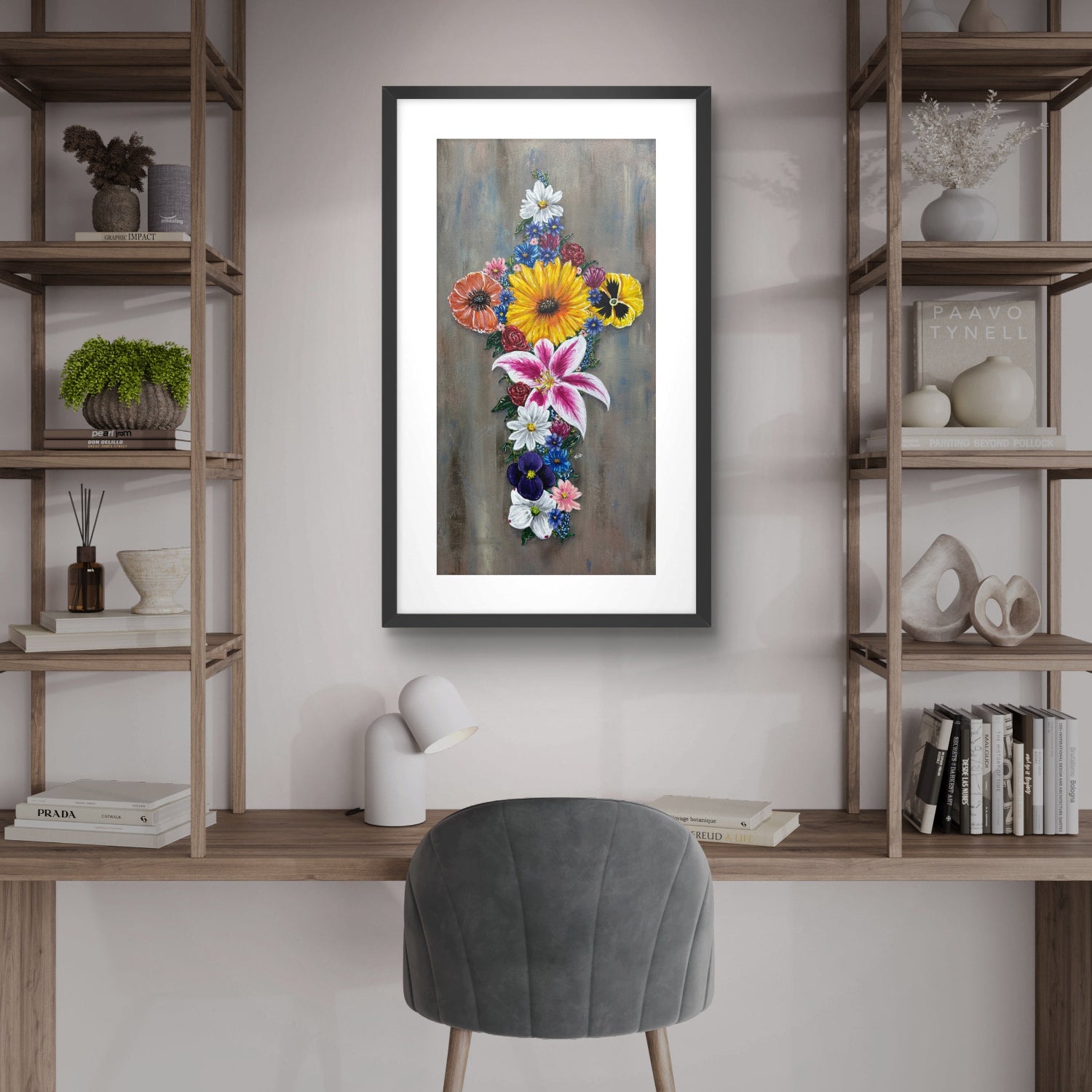 Framed floral cross artwork on a wall above a desk with shelves and a chair.