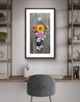 Framed floral cross artwork on a wall above a desk with shelves and a chair.