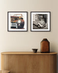 Two framed mini print pictures of vintage cars on a wall above a wooden cabinet paintings by Kris Horton