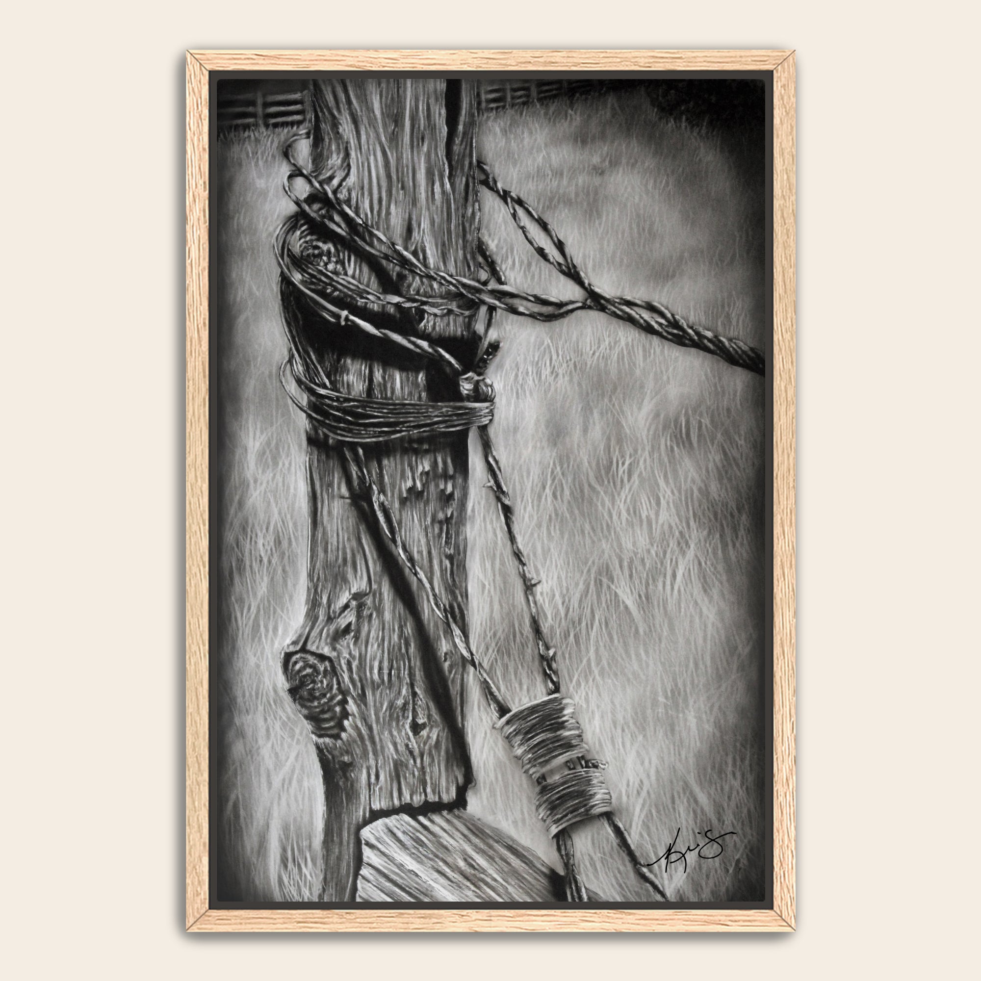 Framed black and white artwork of an old fence post with barbed wire with grass in the background