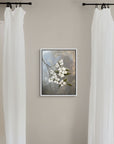 Framed artwork by Kris Horton of a floral branch on a wall between two white curtains.