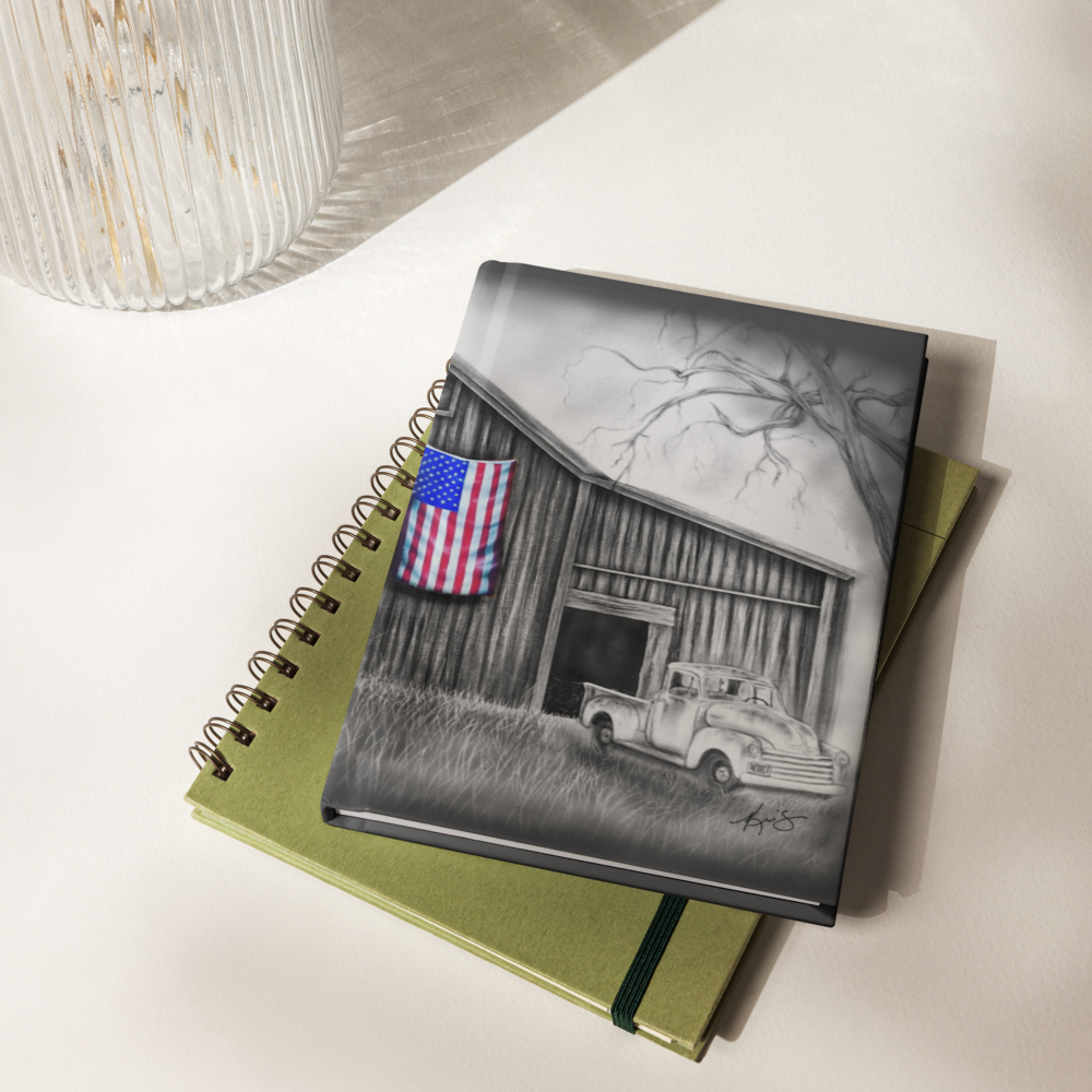 Notebook with a cover featuring a black and white illustration of a barn and truck, with an American flag, painting by Kris Horton