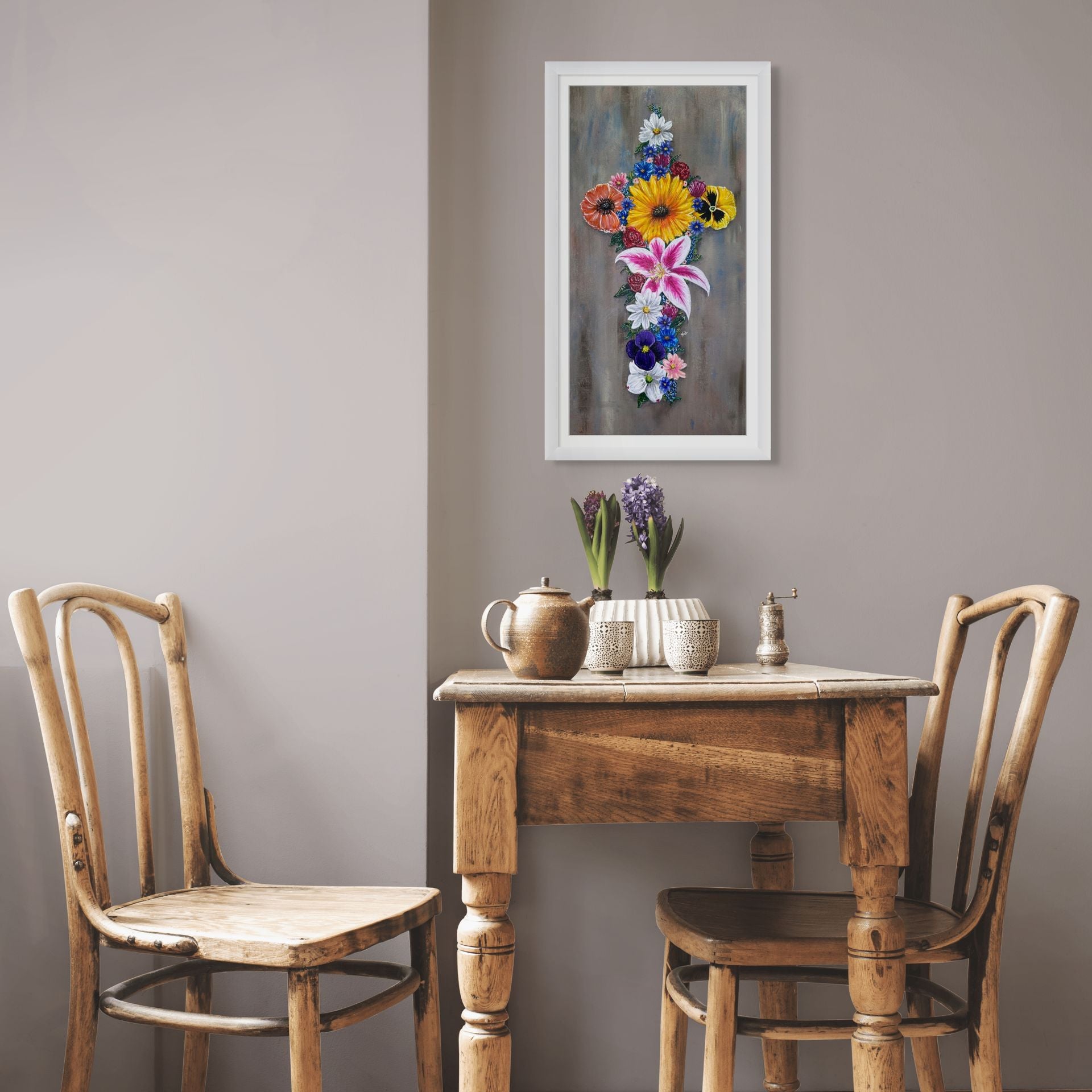 Framed floral cross print by Kris Horton hanging on the wall above a kitchen table.