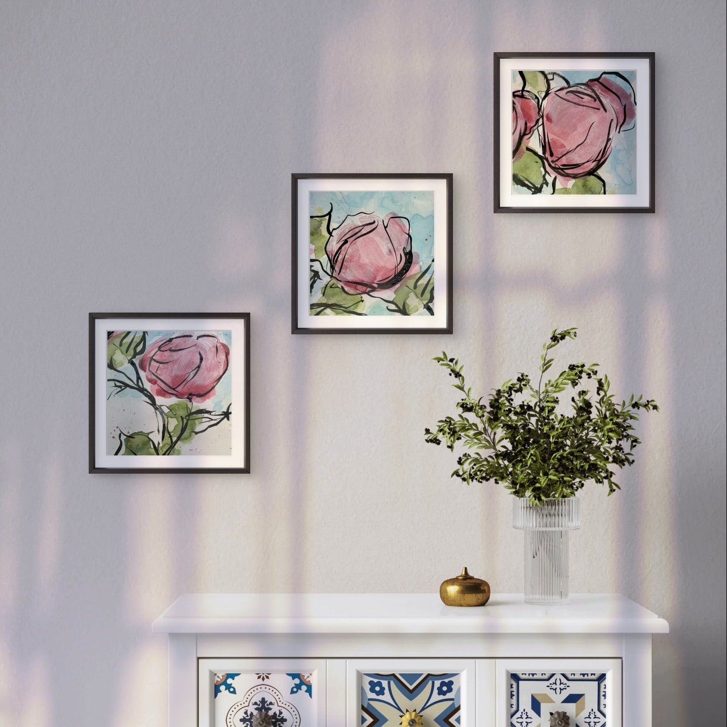 Framed abstract floral prints on a wall above a decorative cabinet with patterned doors, artworks by Kris Horton