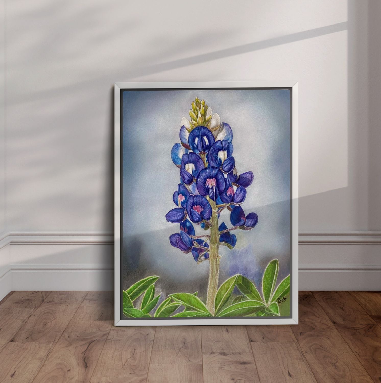 White framed bluebonnet painting leaning on a wall.
