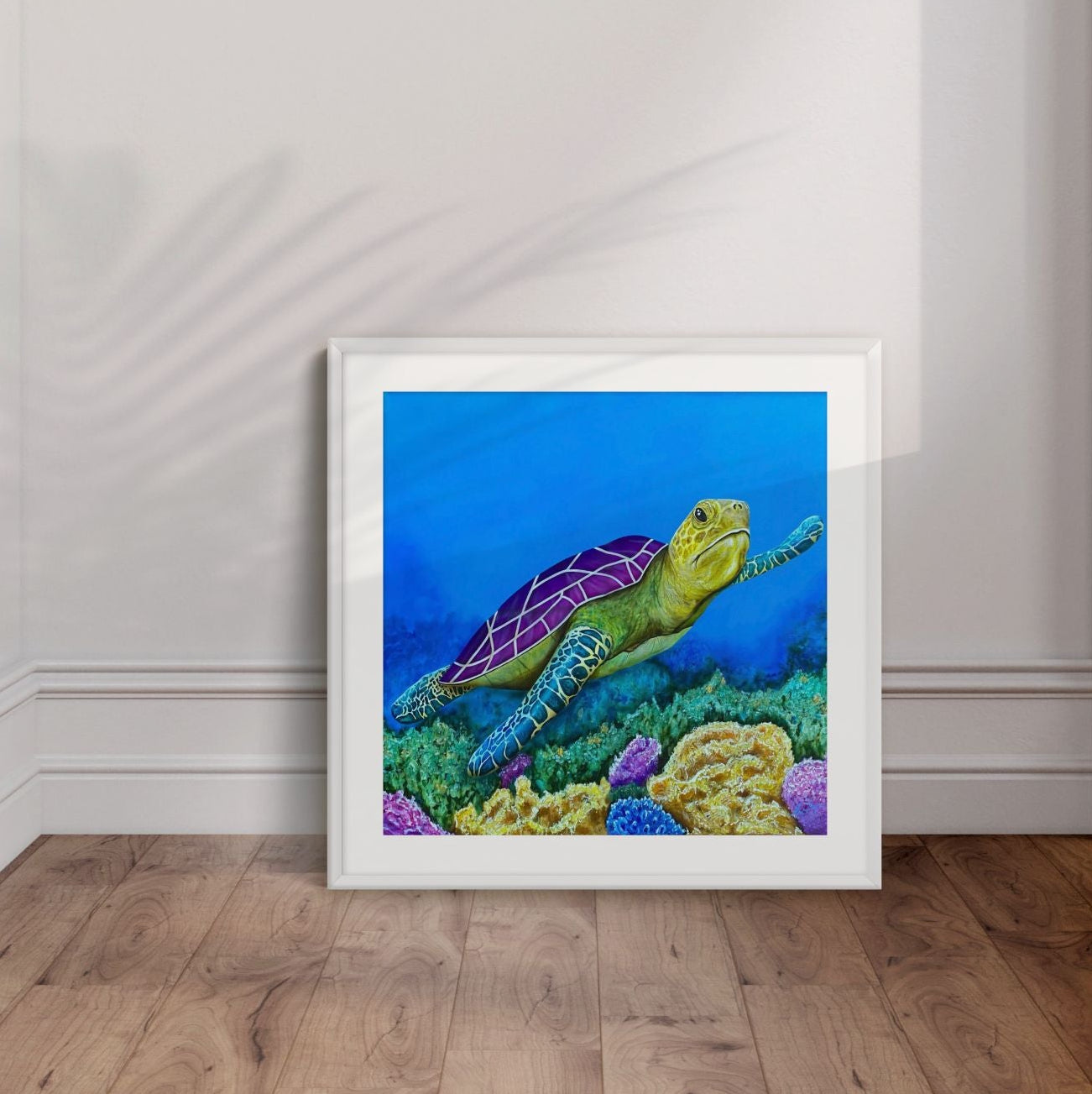 Framed artwork by Kris Horton of a turtle in an underwater scene leaning on a white wall.