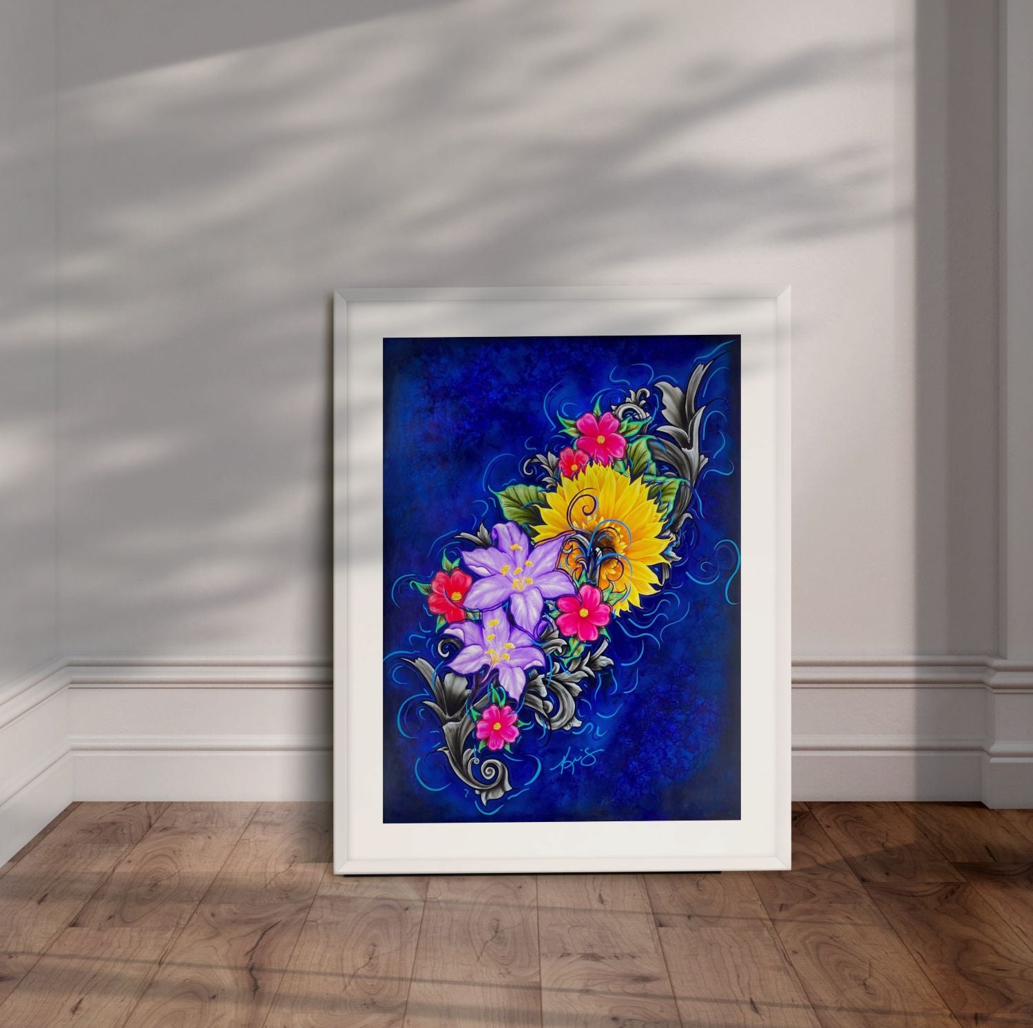 White framed painting of colorful flowers with a blue background leaning against a wall.