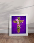 White framed painting of a rustic wooden cross with vines and pink flowers leaning against a wall.